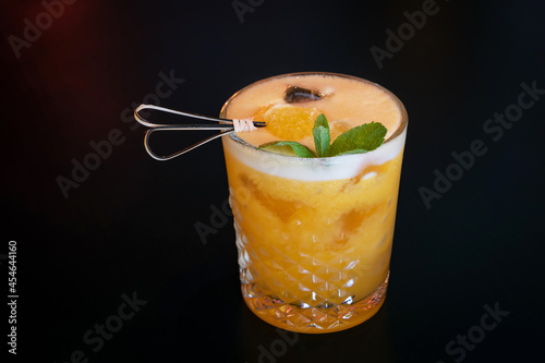 Beautiful yellow citrus cocktail with ice and decoration with an orange piece and mint leaves