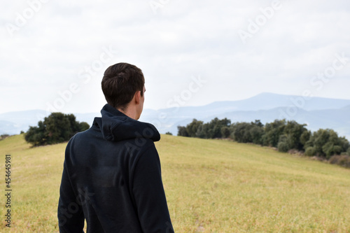 Boy dressed in black observing nature in a meadow