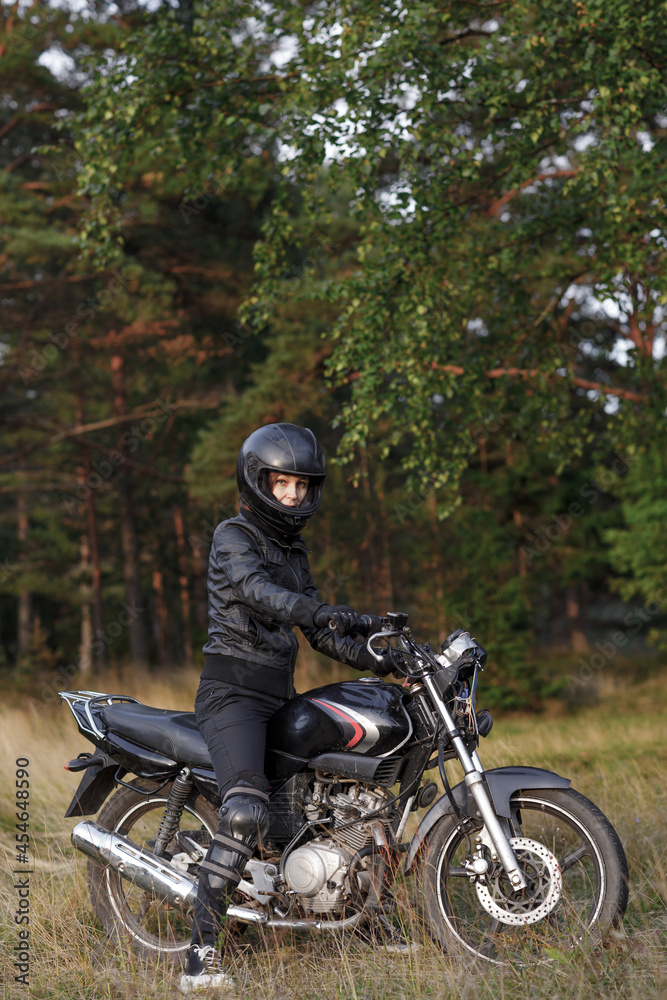 biker girl in black clothes and black helmet on a motorcycle biker girl in black clothes and black helmet on a motorcycle