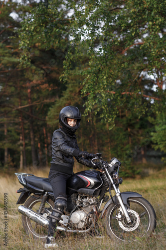 biker girl in black clothes and black helmet on a motorcycle