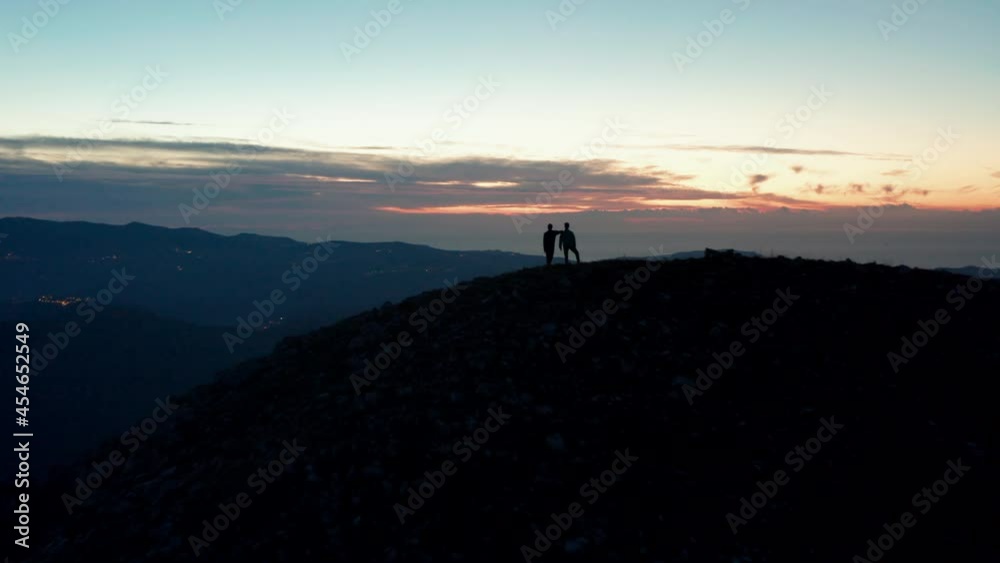 Aerial view of two silhouette men on a rocky mountain, sunrise, in Italy - reverse, drone shot Aerial view of two silhouette men on a rocky mountain, sunrise, in Italy - reverse, drone shot