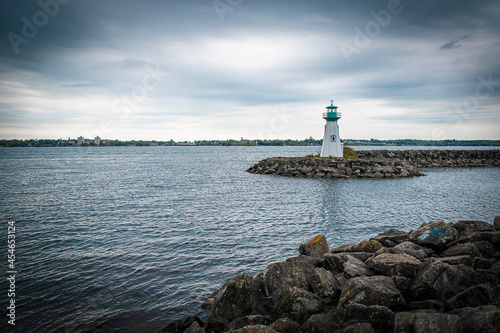 An old lighthouse stands on the rocky breakwater of the harbour in the small town of Prescott, Ontario on a gloomy day.