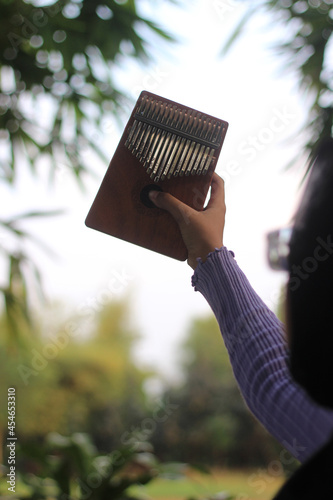 Photo Back pose Muslimah or Islam Girl Hold Kalimba, acoustic music instrument from africa 