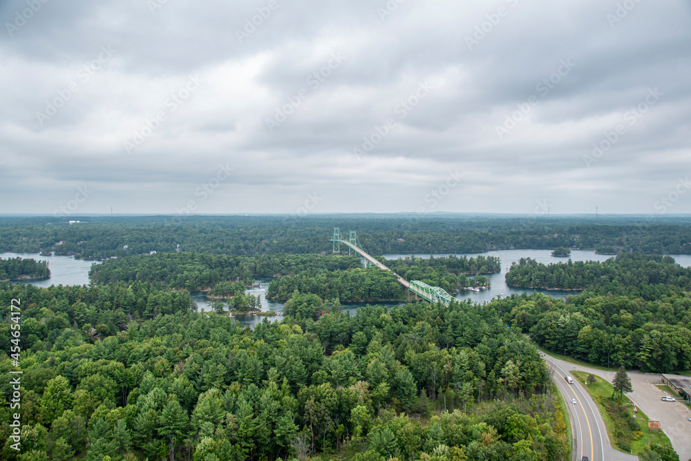 An aerial view of 1000 Islands National Park showing the bridge leading from the mainland onto Hill Island as well as the St. Lawrence River on a gloomy day.
