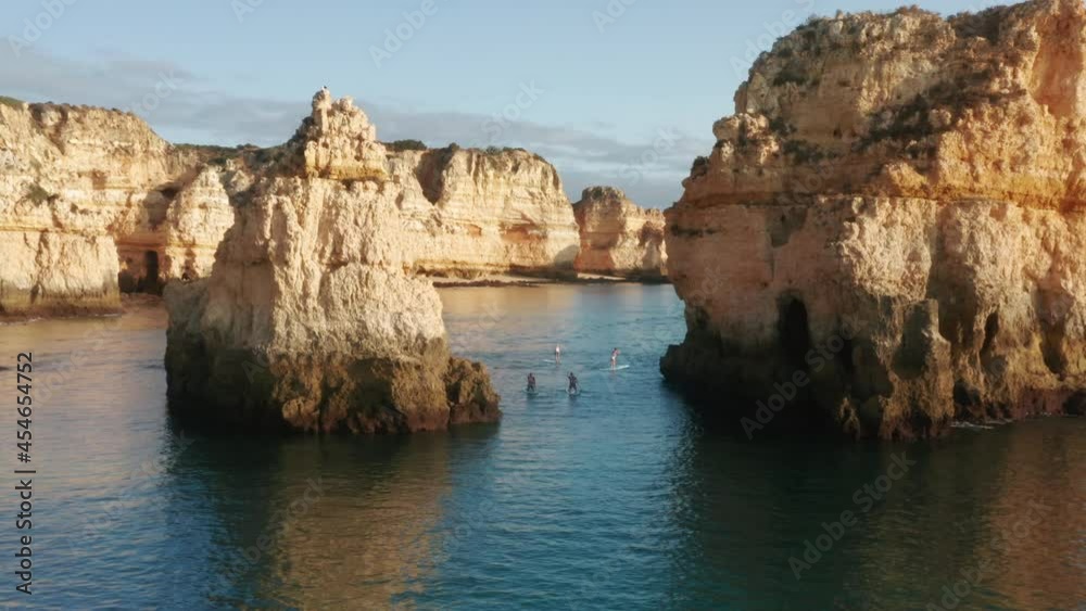 Aerial view of sup surfers paddleboarding between rock formations of Ponta de Piedade, Portugal, Lagos, Europe. Overhead shot of people standing on paddleboards with oars in hands, 4k footage Aerial view of sup surfers paddleboarding between rock formations of Ponta de Piedade, Portugal, Lagos, Europe. Overhead shot of people standing on paddleboards with oars in hands, 4k footage