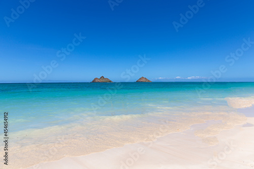 Landscape view of the twin brown Mokolua islands "Mokes" off the coast of Lanikai Beach in Oahu, Hawaii, USA. White sand beach, turquoise water, copy space in clear blue sky. 