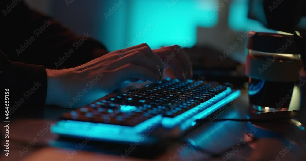 computer hands typing on keyboard programmer coding hacking data on internet cyber crime information hack by anonymous hacker using rgb gaming keyboard with blue backlight