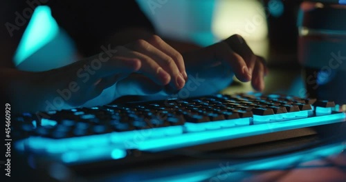 computer hands typing on keyboard programmer coding hacking data on internet cyber crime information hack by anonymous hacker using rgb gaming keyboard with blue backlight photo