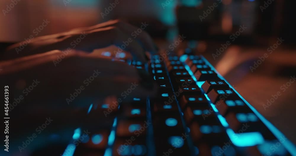 close up hands typing on keyboard programmer coding software gamer using keyboard with blue backlight playing game at night close up hands typing on keyboard programmer coding software gamer using keyboard with blue backlight playing game at night