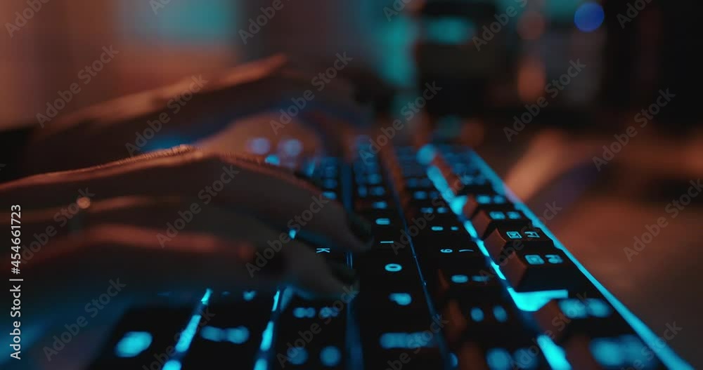 close up hands typing on keyboard programmer coding software gamer using keyboard with blue backlight playing game at night