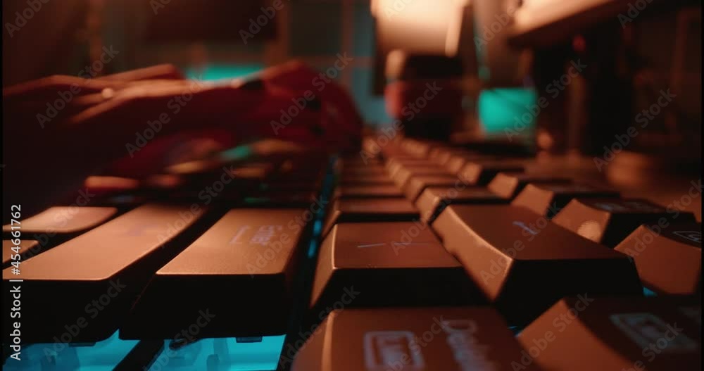 macro hands typing on keyboard computer programmer coding software using keyboard with blue backlight anonymous person hacking at night