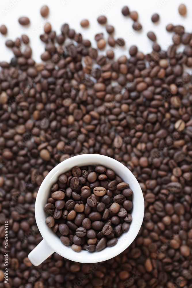 Cup with roasted coffee beans on the background of scattered coffee beans. Top view, copy space. Concept Cup with roasted coffee beans on the background of scattered coffee beans. Top view, copy space. Concept