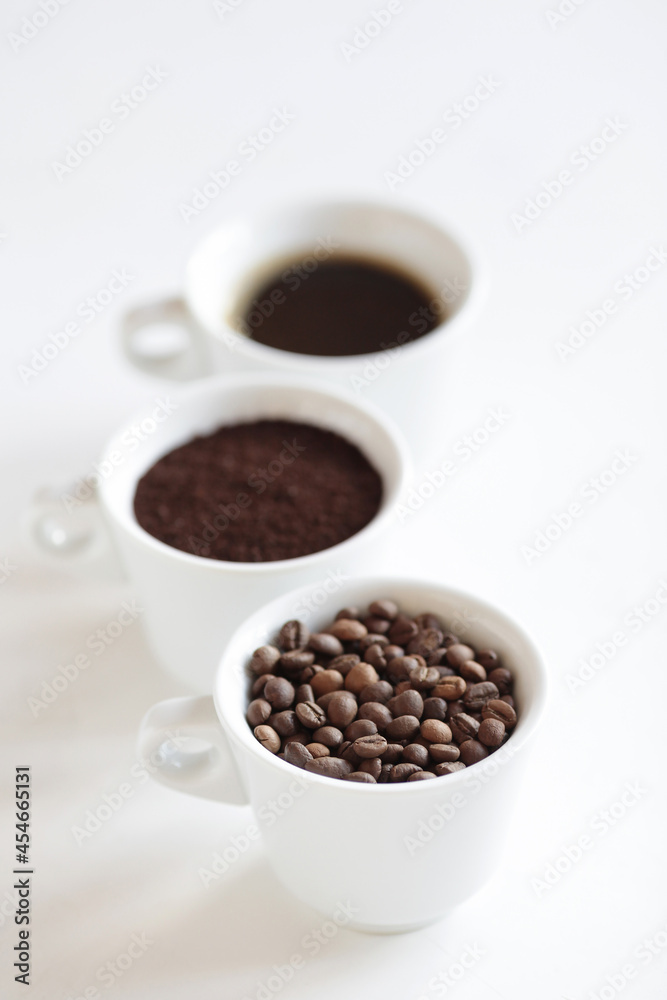 Obraz premium Assorted coffee in white cups, coffee beans, ground and black brewed. White background, copy space.