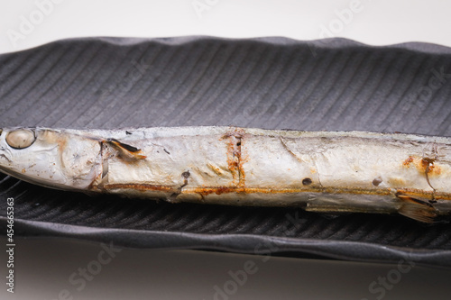 白バックで黒いお皿にのっている焼いた秋刀魚のアップ　fish