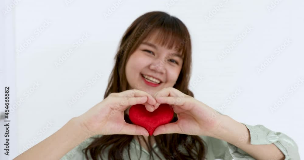 Young and cute Asian woman holding red hearth shape and offer it to camera with smile and happy face. Young and cute Asian woman holding red hearth shape and offer it to camera with smile and happy face.
