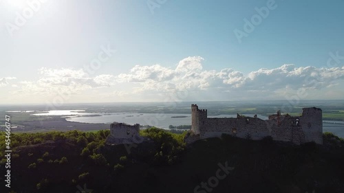 Drone closing in to Děvičky castle ruins in late sun with the dam Nové Mlýny in Background - South Moravia - Czech republic. photo