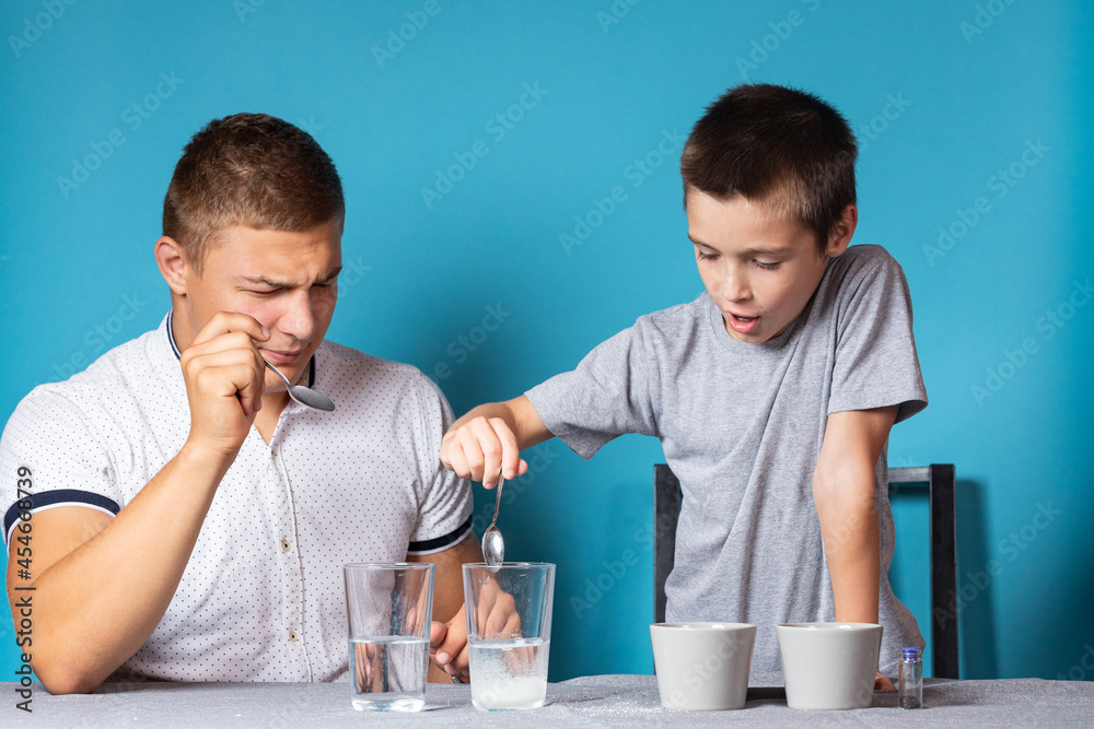 Chemistry education and study concept. Close-up of a boy and his father, scientists pour water into a bottle with chemical elements, for experiments at home Chemistry education and study concept. Close-up of a boy and his father, scientists pour water into a bottle with chemical elements, for experiments at home