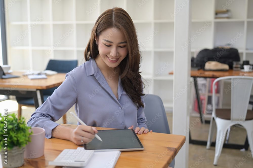 Smiling businesswoman working with digital tablet in modern workplace.
