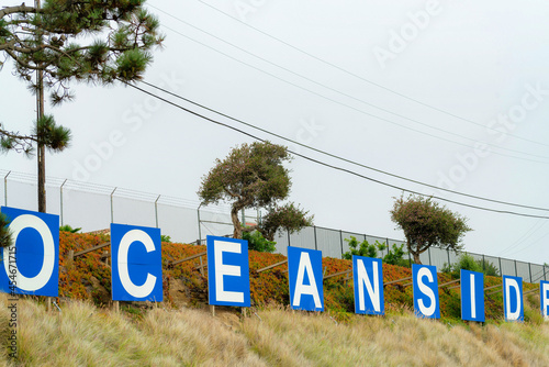 Fotografia Scenic view of oceanside signage on a hill under a cloudy sky