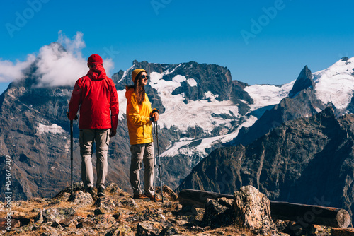 Young couple doing Nordic walking in the mountains, rear view. An active couple is engaged in Hiking. A young couple is engaged in tracking. Trekking and Nordic walking. Hiking. Copy space