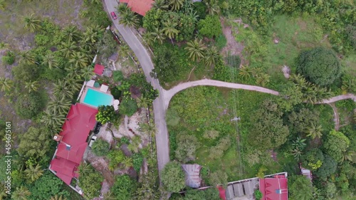 An aerial drone shot of rural place, countryside of greens and trees visible from above the sky. Car and few vehicles motorcycle seen in the road. Near beaches and a popular tourist destination. photo