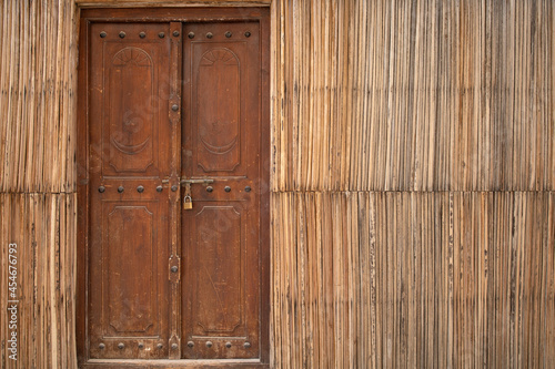 An old wooden closed door in straw wall with copy space