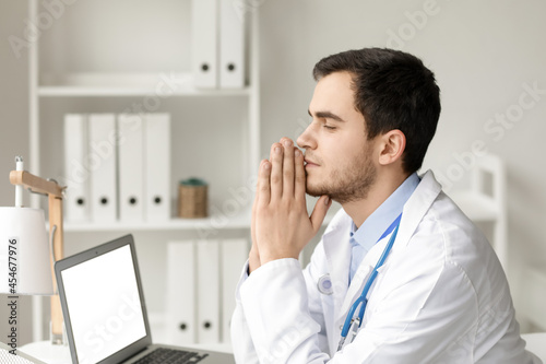 Religious doctor praying in...