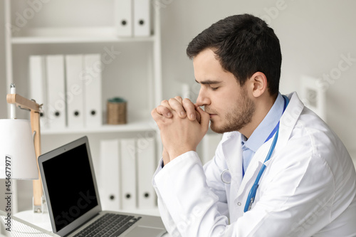 Religious doctor praying in...