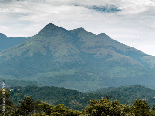 Landscape oriented wallpaper poster background of highest mountain in wayanad Chembra peak hills on a hazy day in Meppadi.