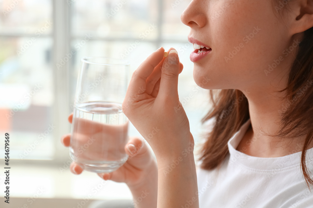 Young woman taking pills at home Young woman taking pills at home