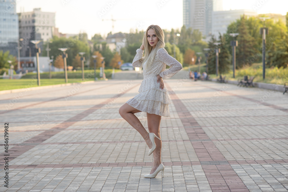 Portrait of a stylish and attractive Caucasian blonde girl posing in the summer on the street. Fashion concept.