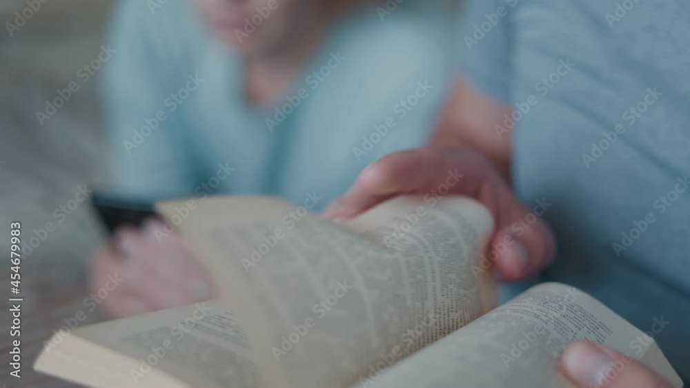 girl and a guy are reading a book and looking for information on the phone on the Internet