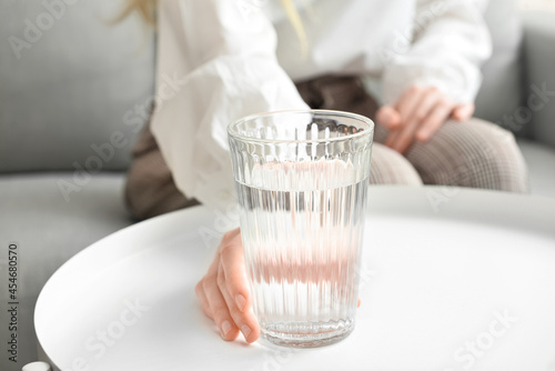 Woman with glass of water at home, closeup