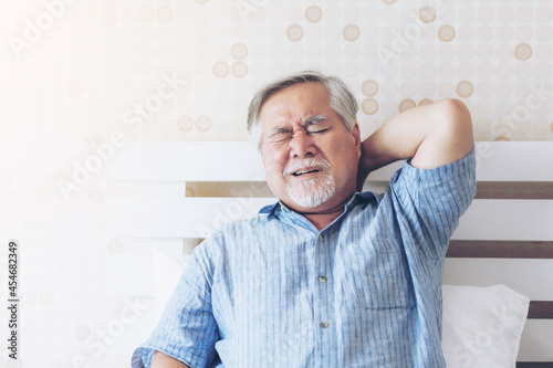 Senior Asian man , old man he wake up and sat on the bed , He had pain in the nape of his neck caused by sleeping on a pillow that is not correct posture - Senior people unhealthy diseased concept