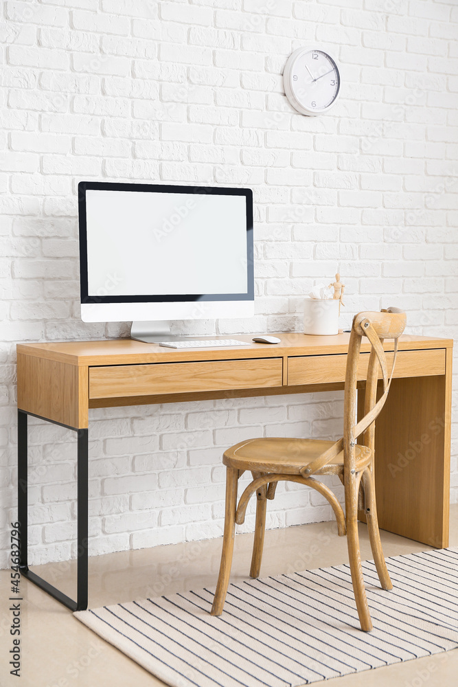 Fototapeta premium Modern workplace with computer near brick wall