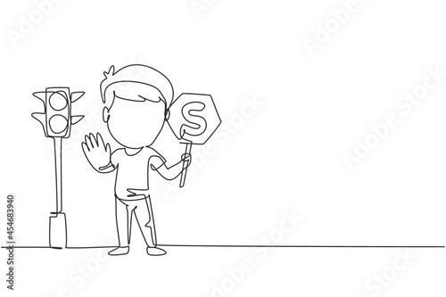 Single continuous line drawing little boy holding stop sign in arm standing near road, pedestrian rules for kids, traffic light in vector style. Child holding stop sign. Dynamic one line draw graphic