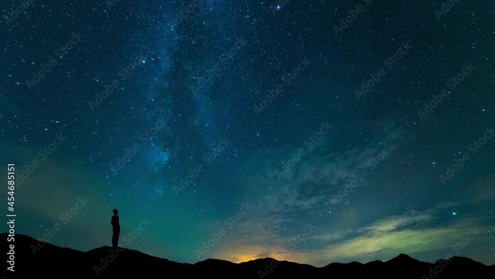 The man stand on mountain top on a starry sky background. time lapse