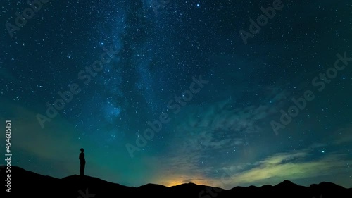 The man stand on mountain top on a starry sky background. time lapse