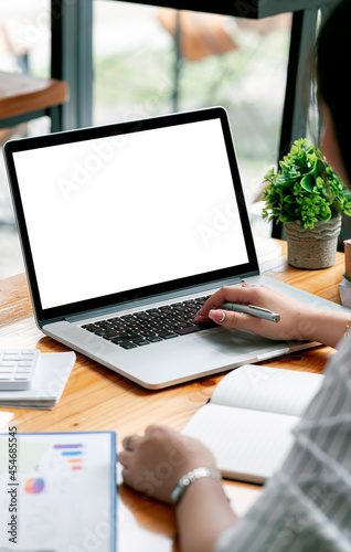 Cropped shot of woman hand working on laptop computer and peper work while sitting at the table.