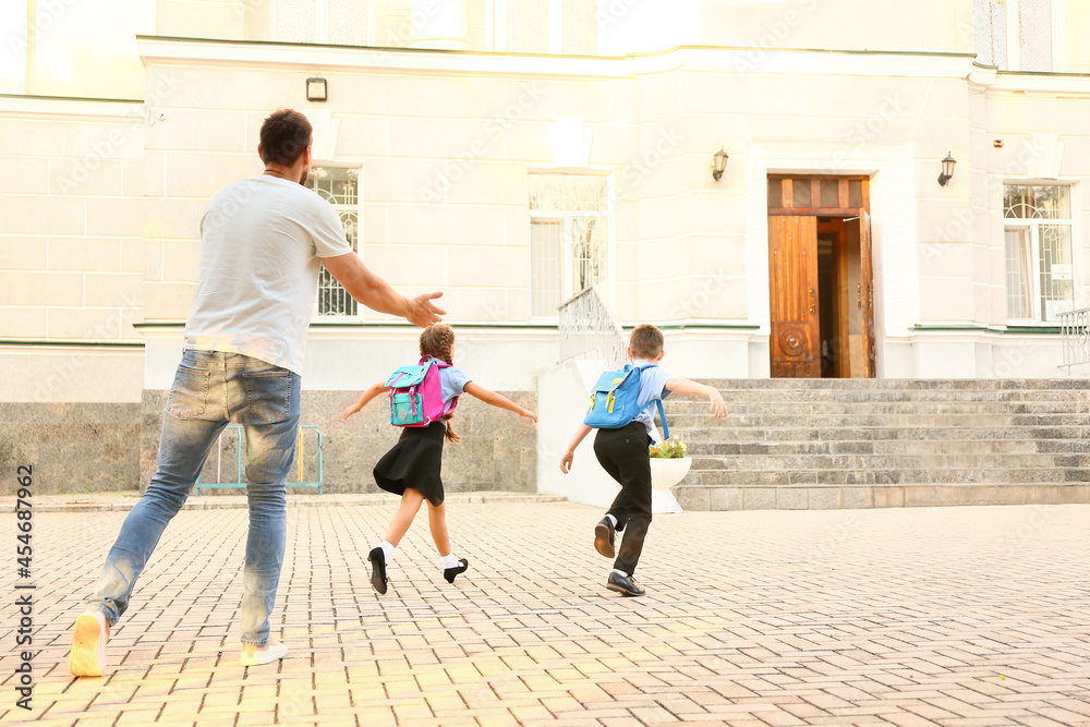 Cute little children going to school with their father