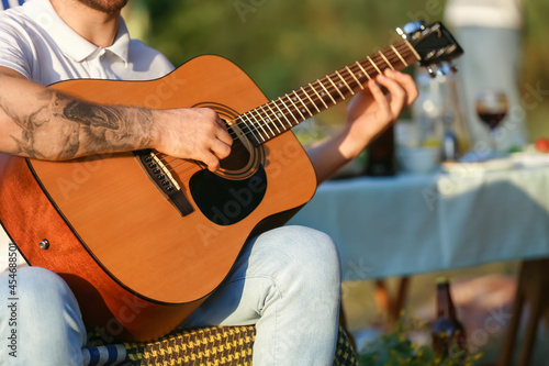 Young man playing guitar at barbecue party on summer day