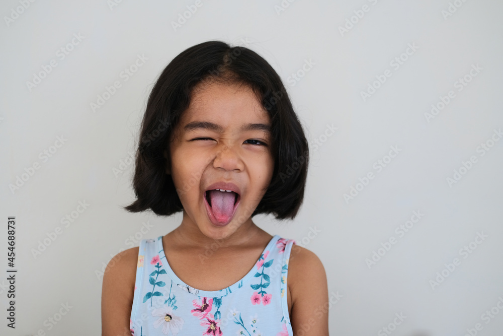 Close up portrait of Asian little kid face doing funny expression with her tounge out