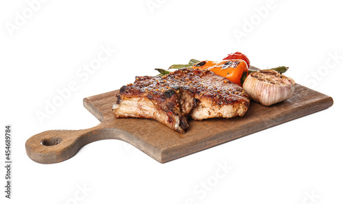 Wooden board with tasty pork steak and grilled vegetables on white background