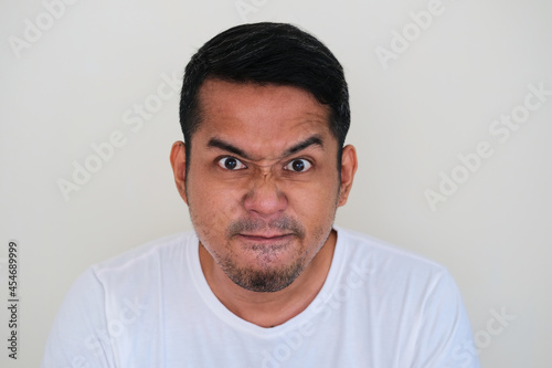 Close up portrait of Asian man face doing angry expression photo