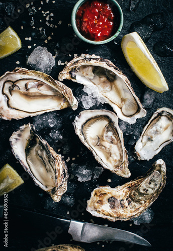 close-up on oysters with sauce and lemon on a black background top view
