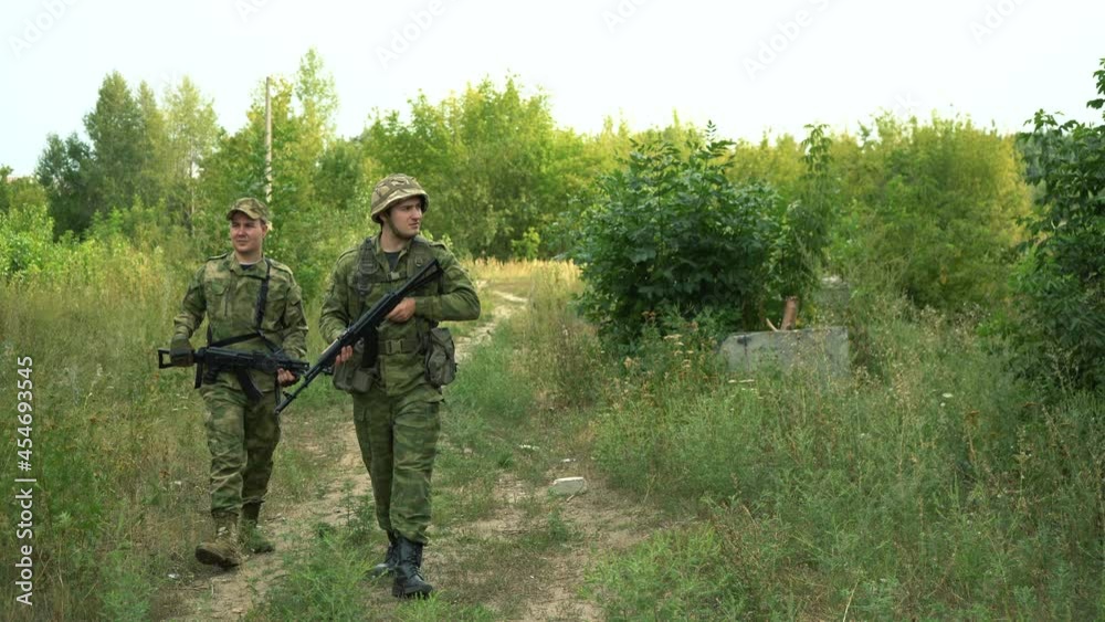 soldiers with weapons are walking along a dirt road in the forest soldiers with weapons are walking along a dirt road in the forest