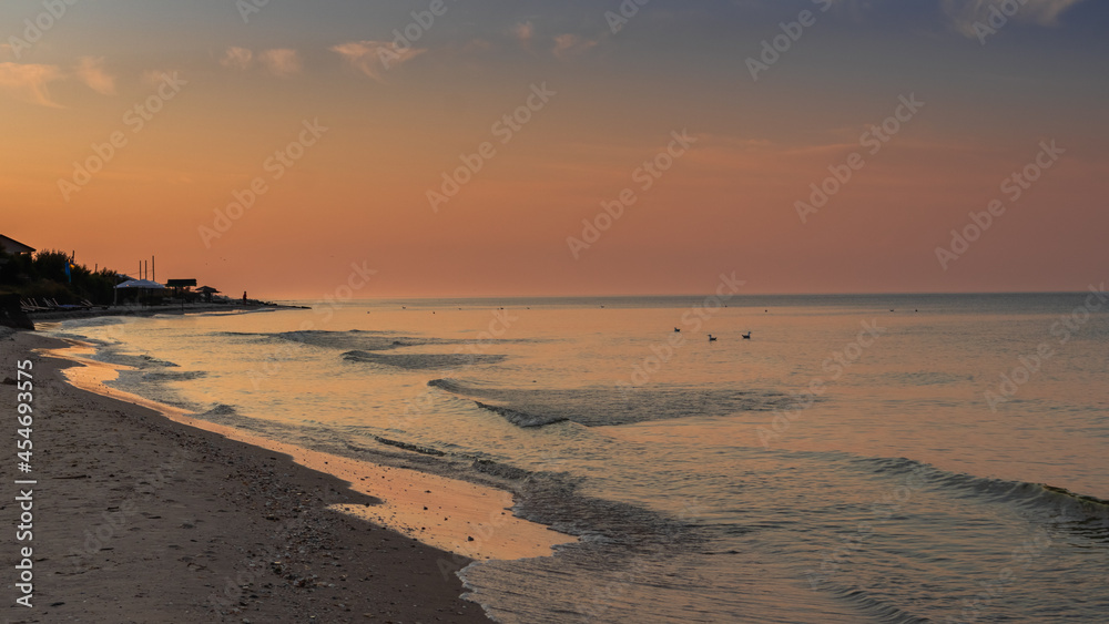Bright pink colors of dawn on the coast of the Black Sea in the early summer morning. Ukraine.
