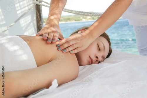 Woman having back massage in spa tent on the beach.