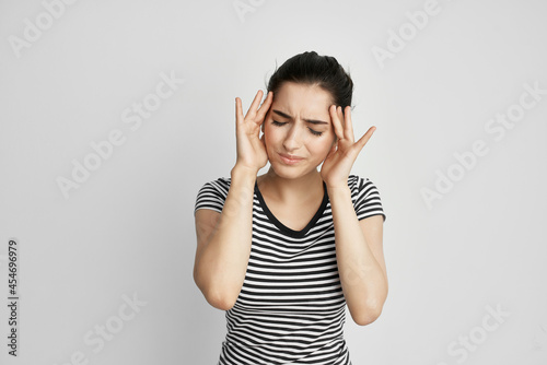 sick woman in a striped t-shirt pain in the neck light background