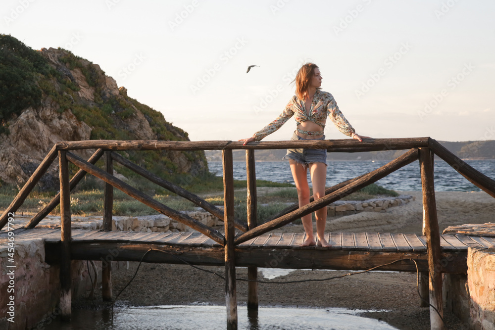 Outdoor portrait of woman standing on wooden bridge